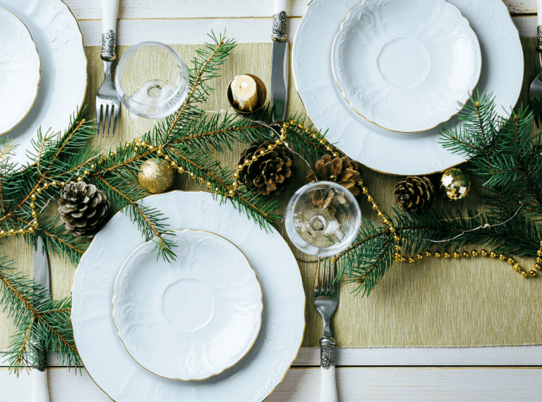 Holiday greens on the dining table with pinecones and wine glasses