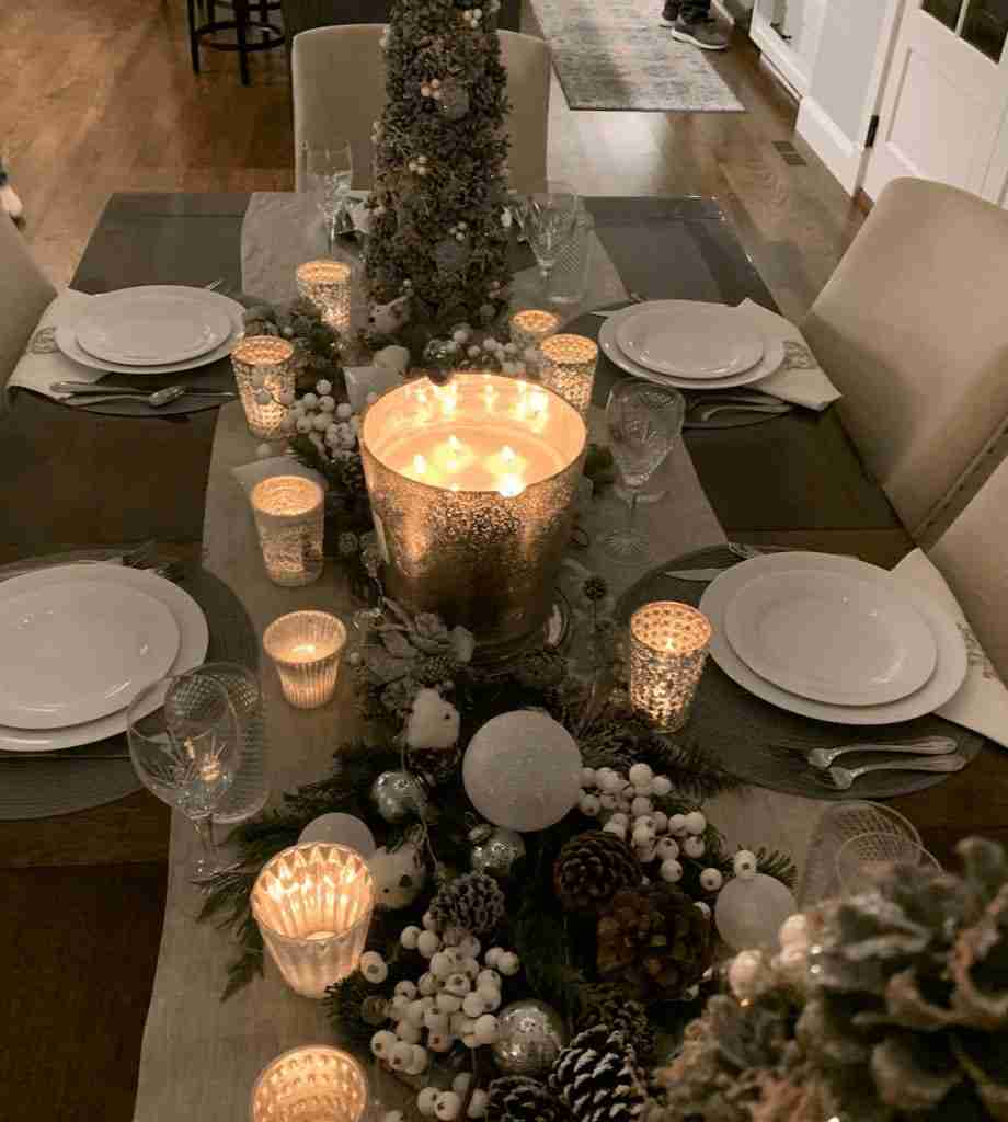 Holiday tablescape with candles and greens down the center of the table