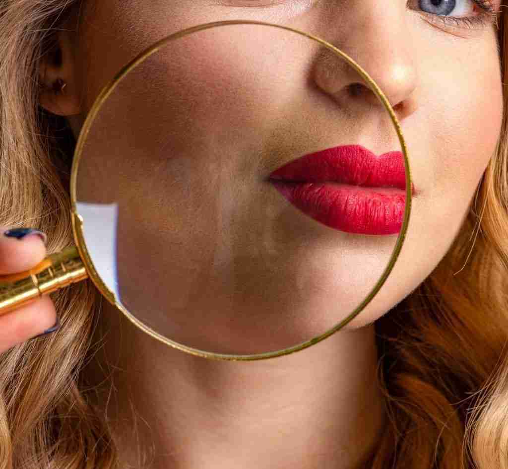 Woman checks skin face using loupe.