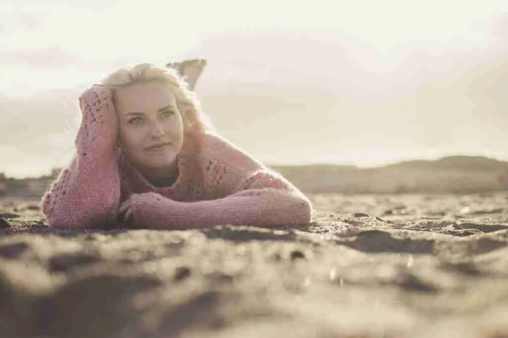 Attractive lady lay down at the beach on the sand in winter