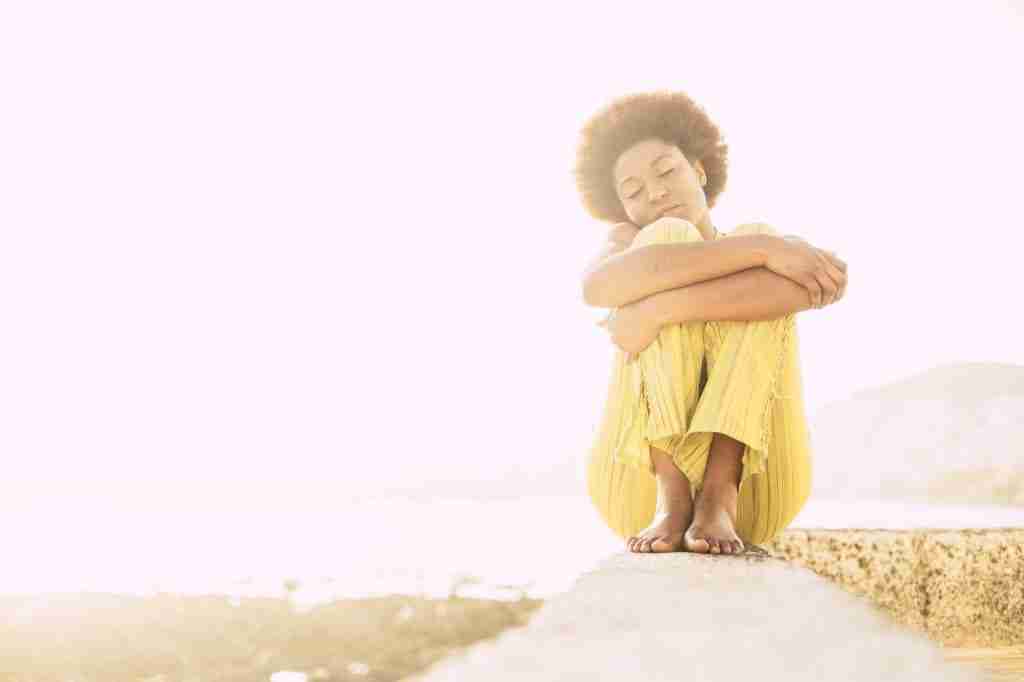 Lonely cute afro american hair style girl sitting and hugging herself in outdoor feeling the nature