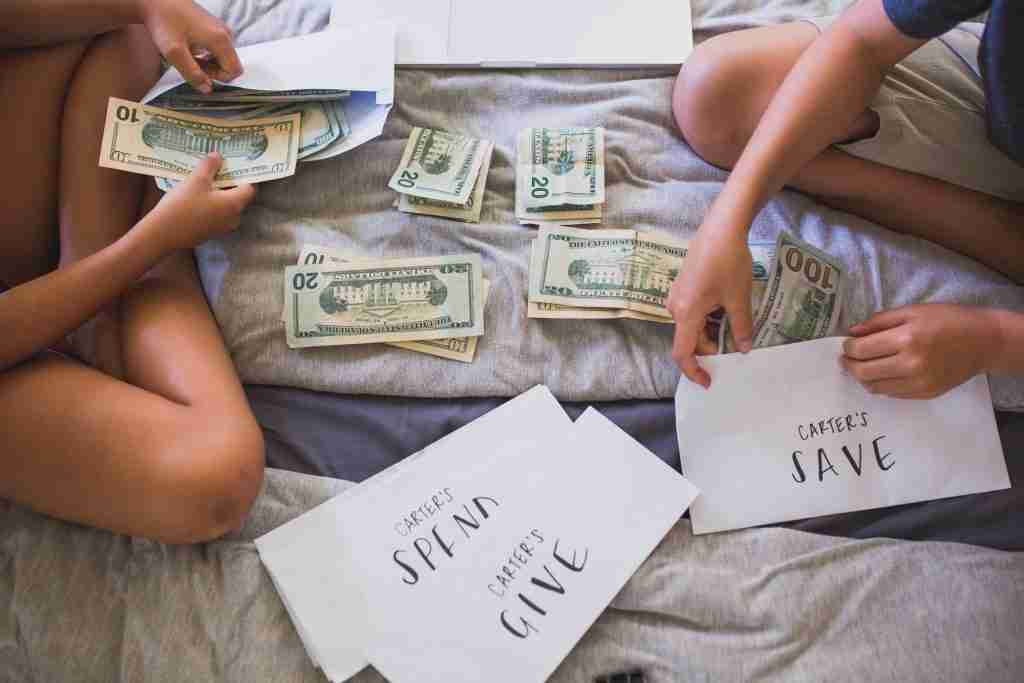 Kids dividing cash money into save, spend and give envelopes