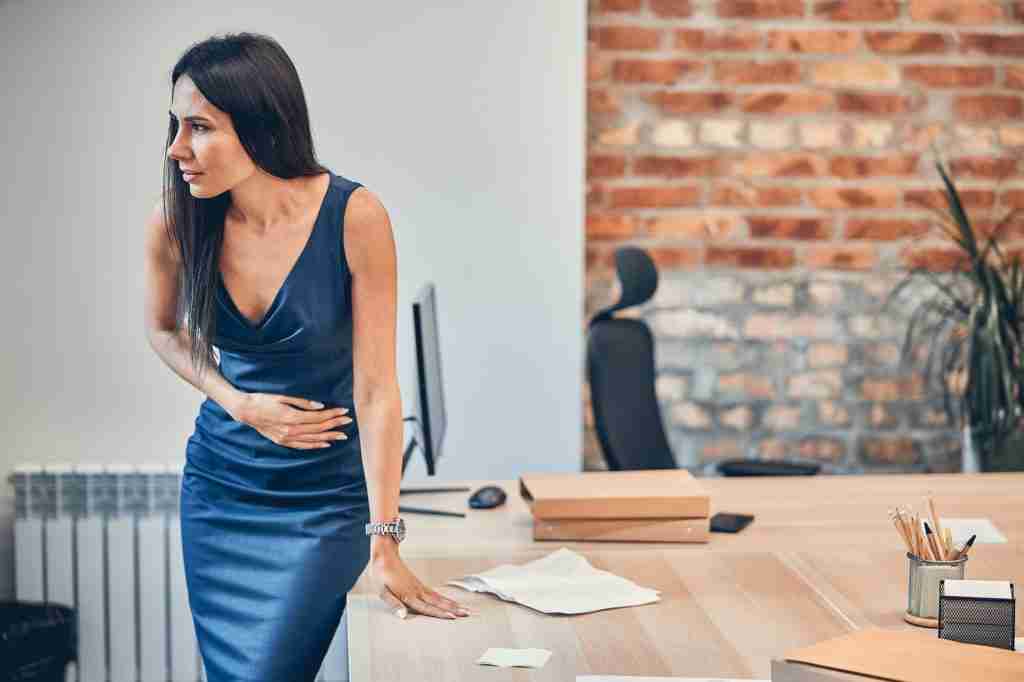 Business woman with stomach ache in office