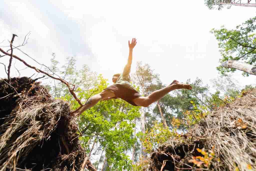 Young man making a jump in the forest.