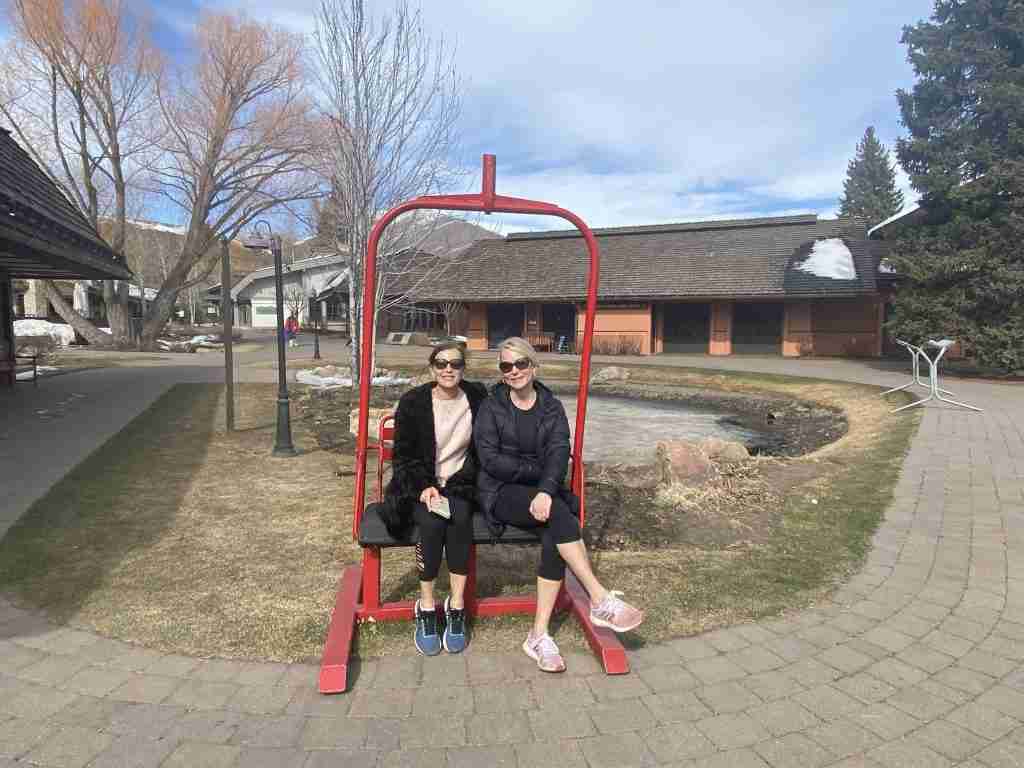 Two women sitting on a ski lift chair