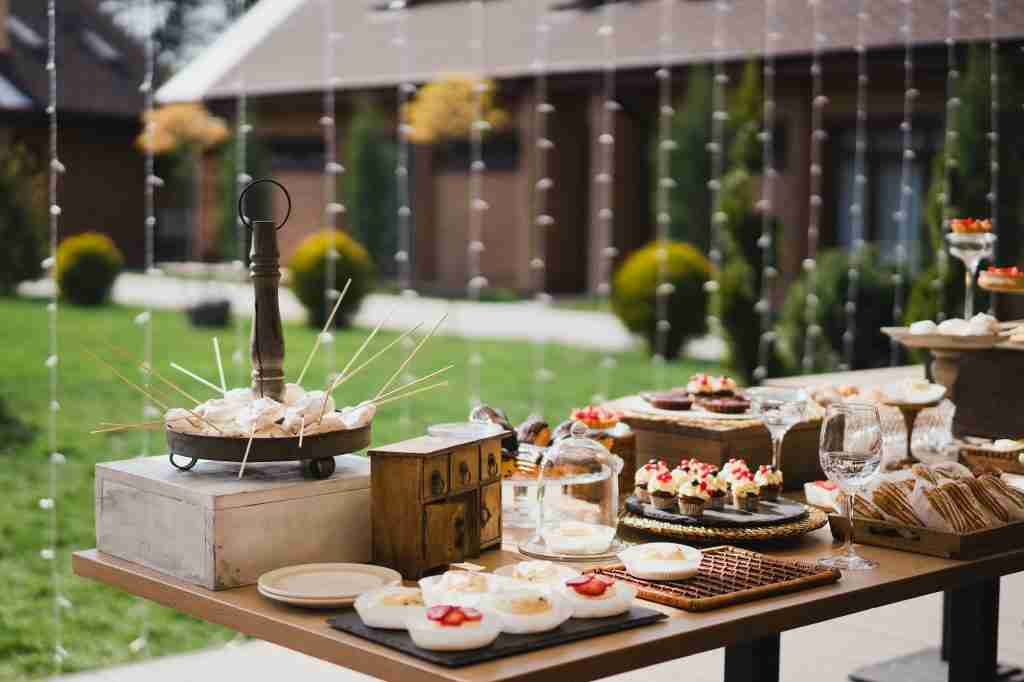 Candy bar with tasty desserts and appetizers at wedding reception. Decorated with flower composition