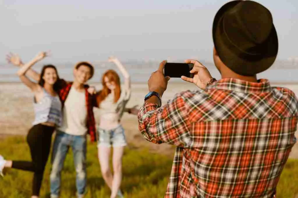 Young black man taking photo his friends on mobile phone