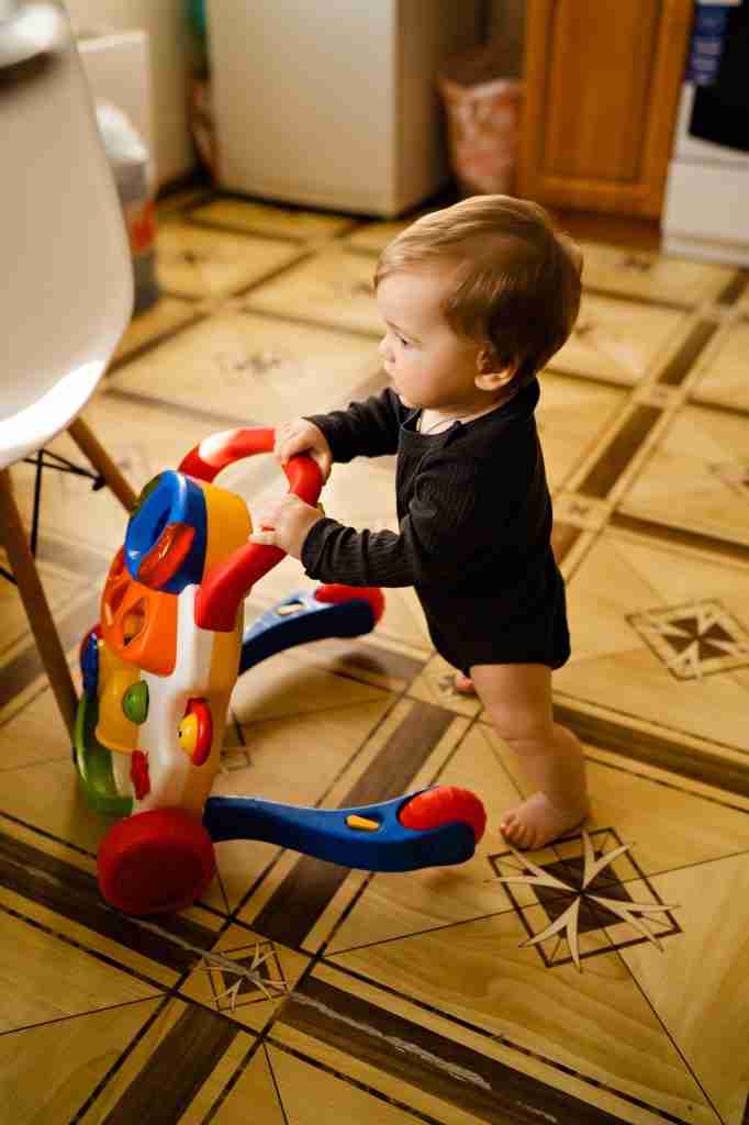 Cute baby with toy walker at home