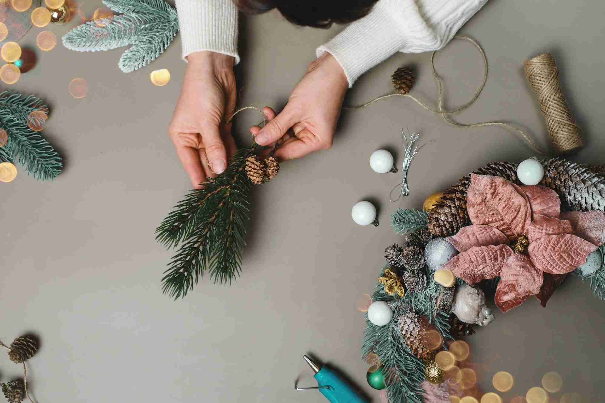 Hands making Christmas wreath with fir branches, Flat lay.