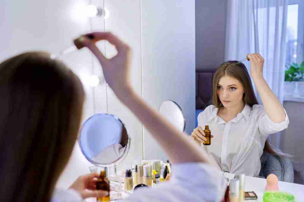 Young woman treating her hair using medical drops