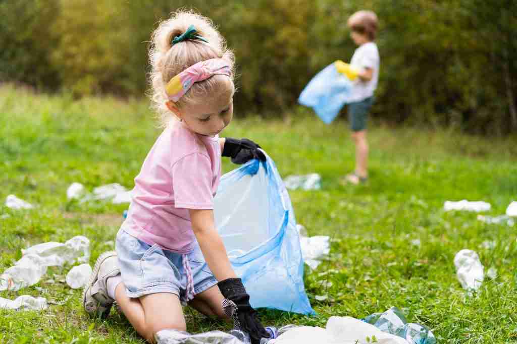 children remove plastic garbage and put it in a biodegradable garbage bag in the open air