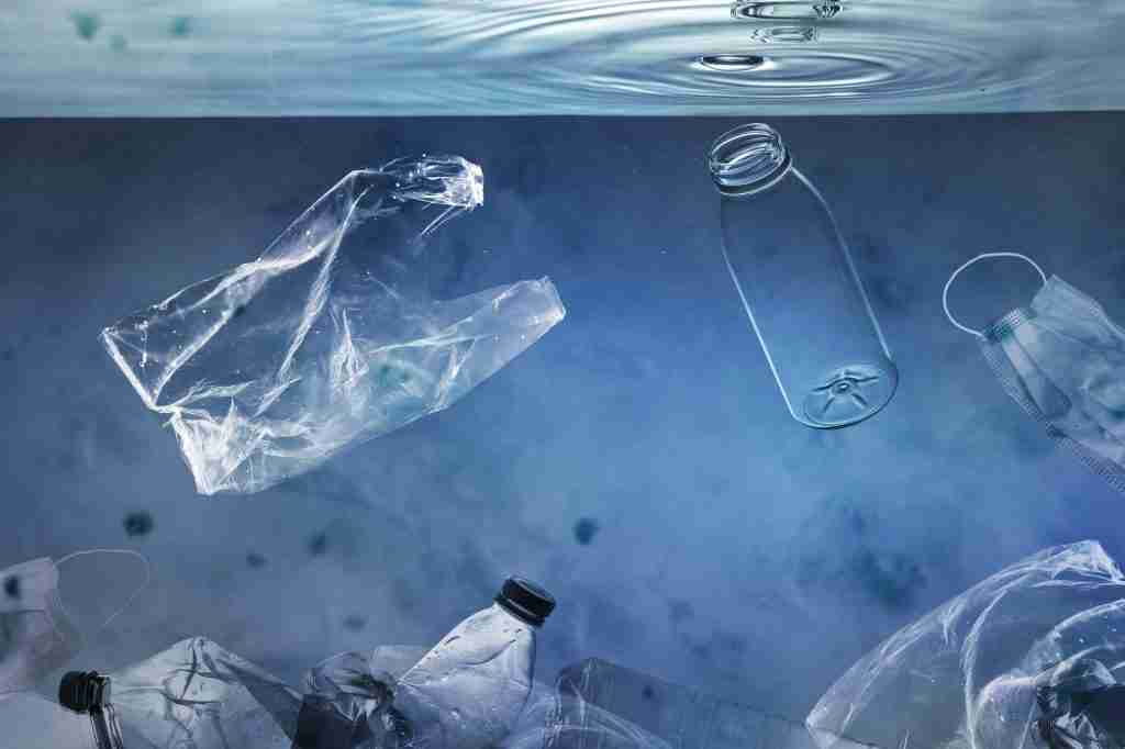 Ocean pollution campaign with plastic bags and used bottles floating