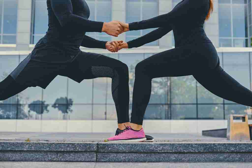 Athletic couple is stretching over modern building background.
