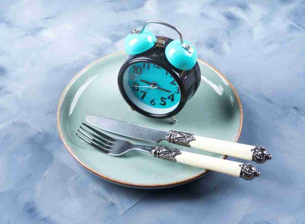 Intermittent fasting concept with blue alarm clock