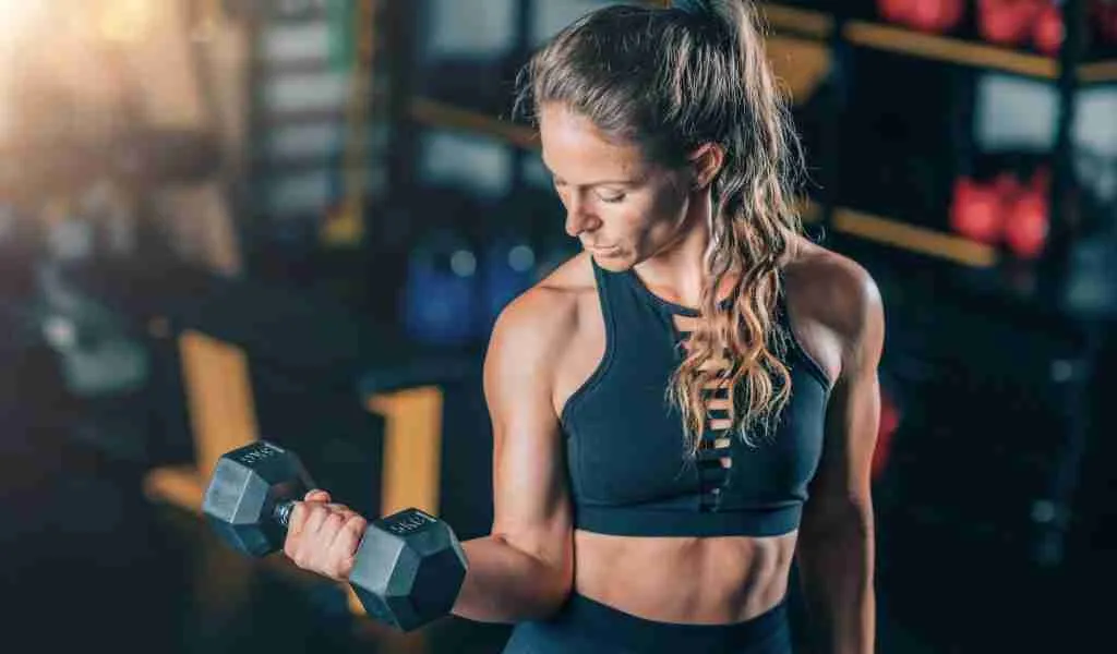Female Athlete Doing Biceps Exercise with Dumbbells. Strength Training.