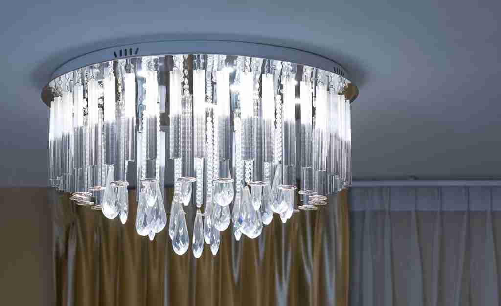 Round crystal chandelier with lighting on ceiling in night living room
