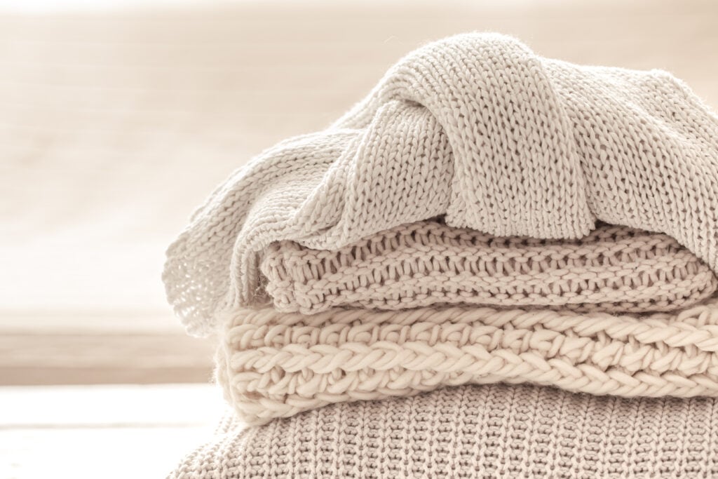 A stack of neatly folded warm knitwear, wool close up.