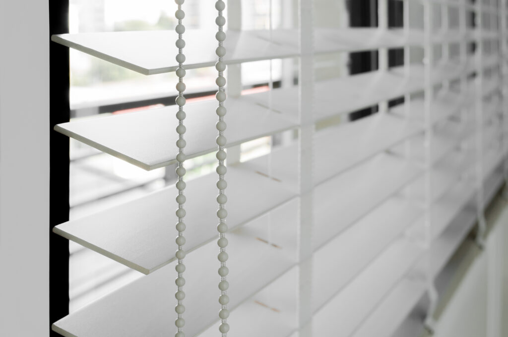 Closeup white color wooden blind with white ladder tape curtains.