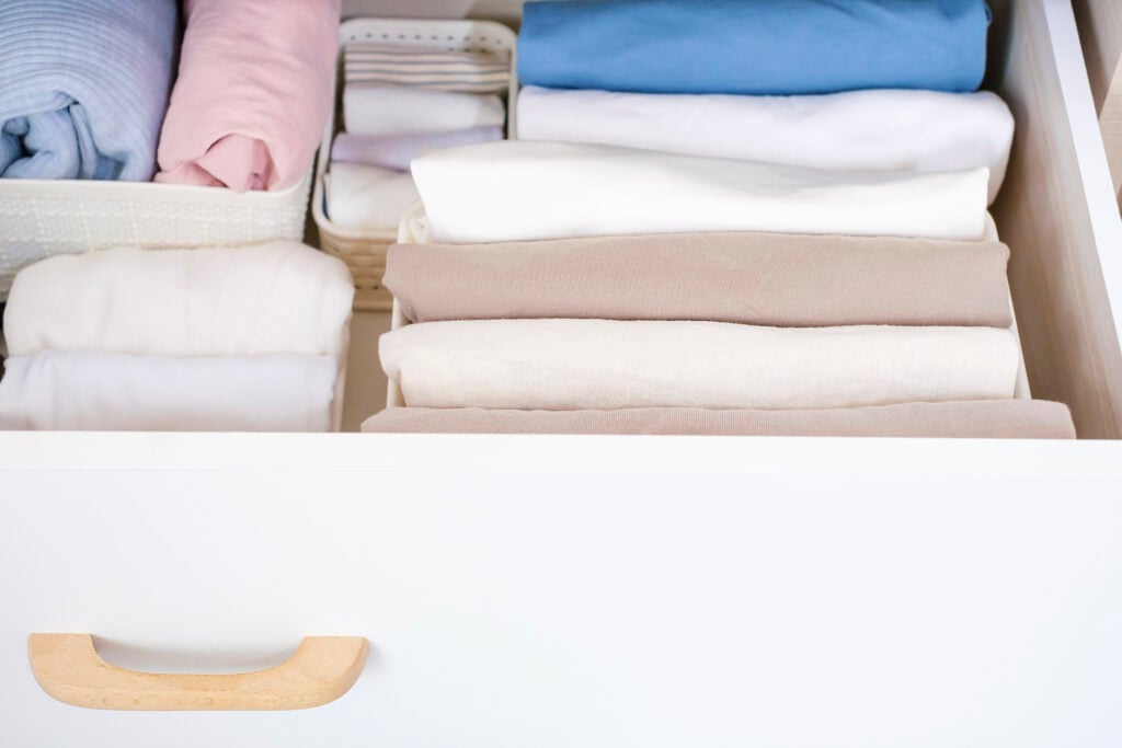 Clothes folded in a box in a chest of drawers close-up, space organization concept.