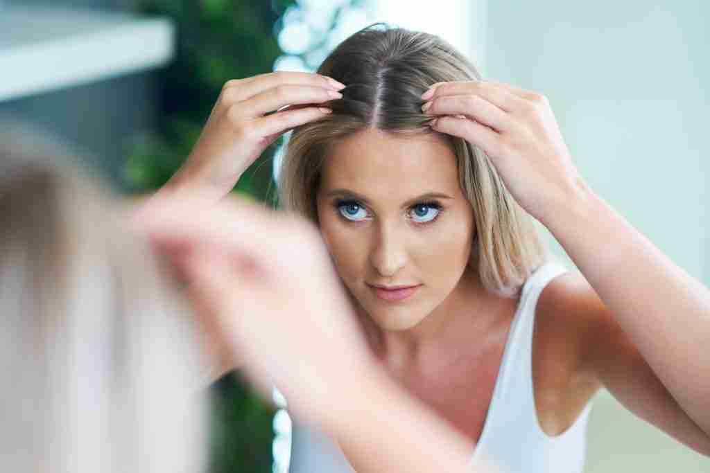 Happy woman brushing hair in bathroom having problem with hair loss and hair thinning