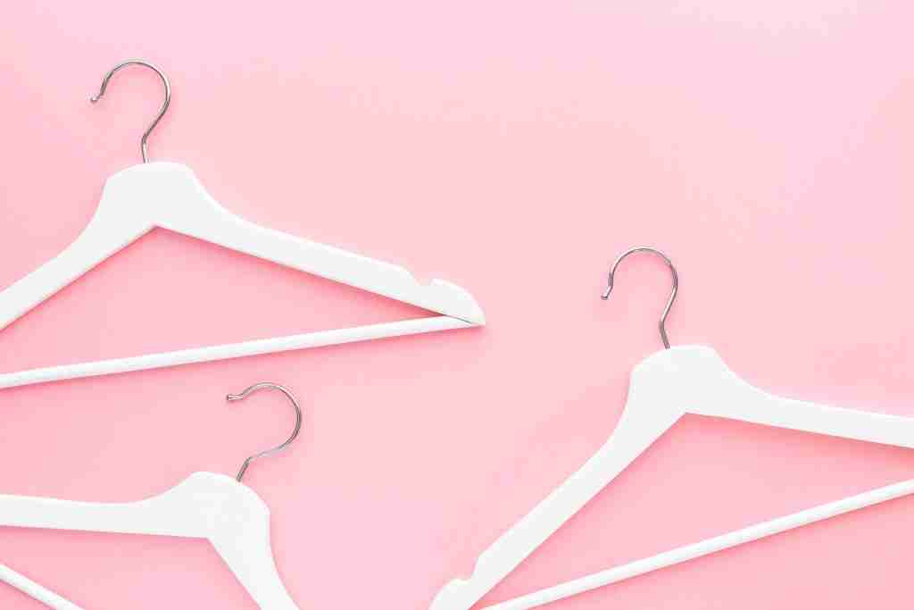 White hangers on pastel pink background