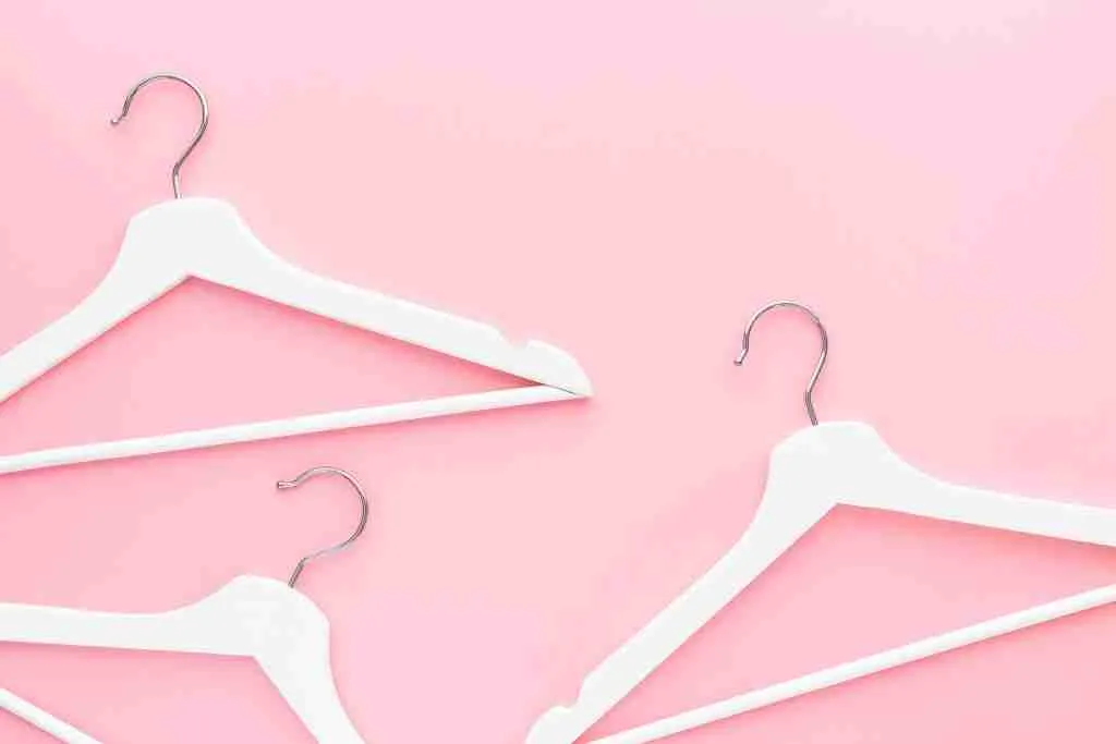 White hangers on pastel pink background