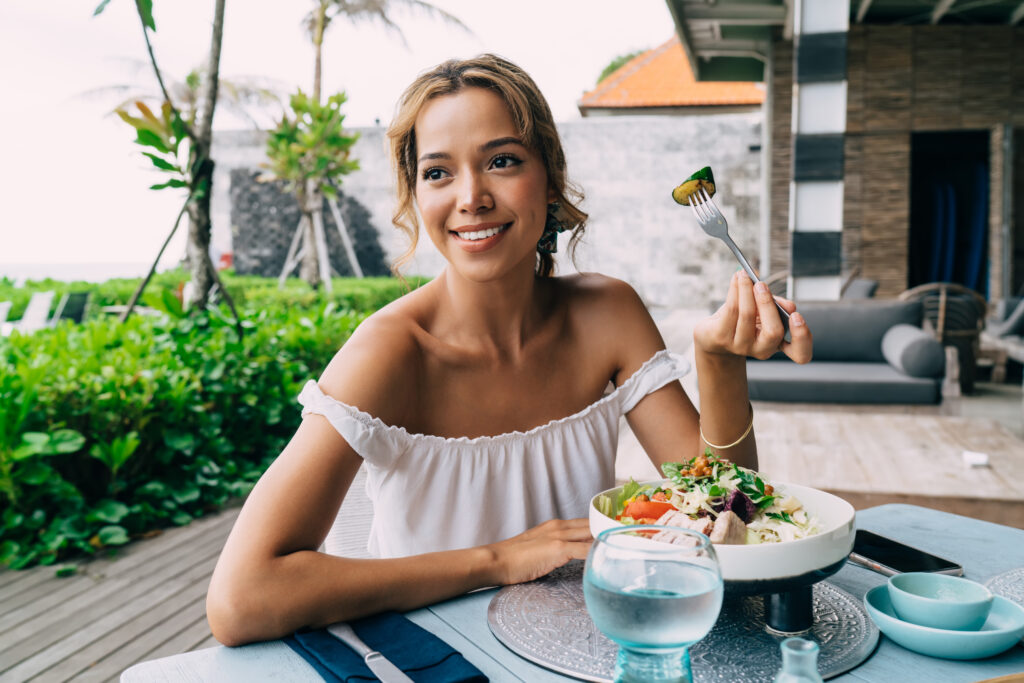 Happy woman smiling and eating healthy breakfast with fork