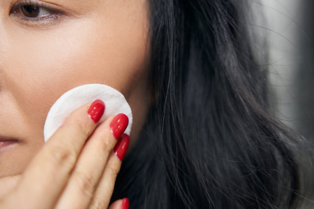 Woman with cotton pad in hand cleaning her face