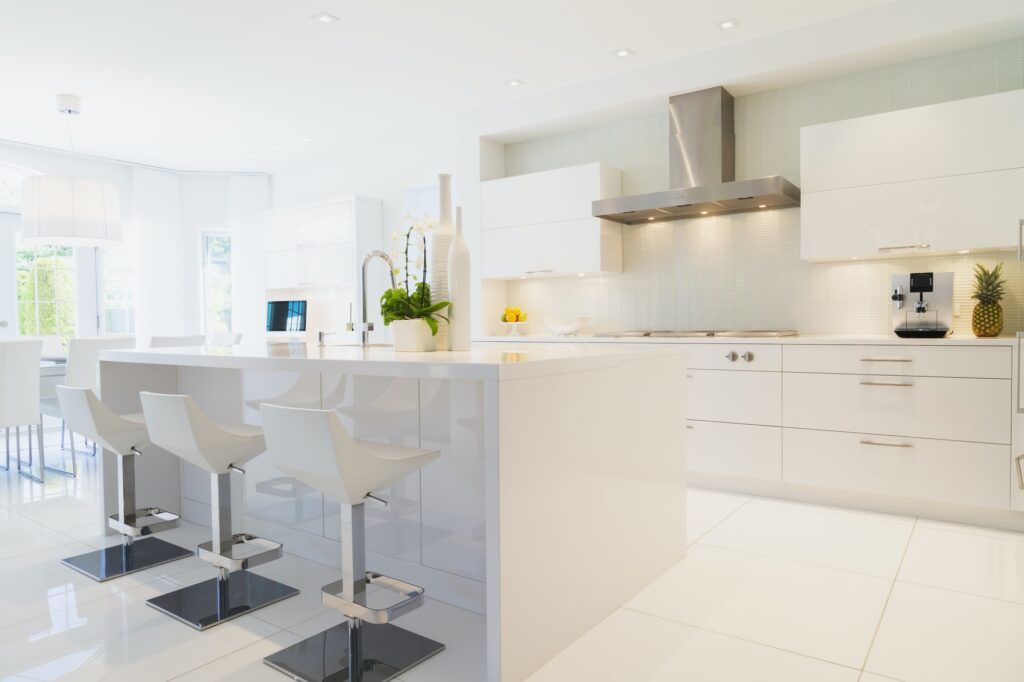Modern kitchen with white Italian lacquered kitchen island and chrome barstools inside luxury
