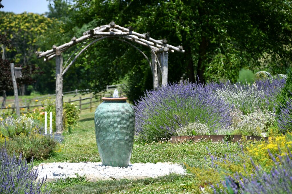 A fountain water feature at a lavender farm with colorful flower garden fields and rustic fences