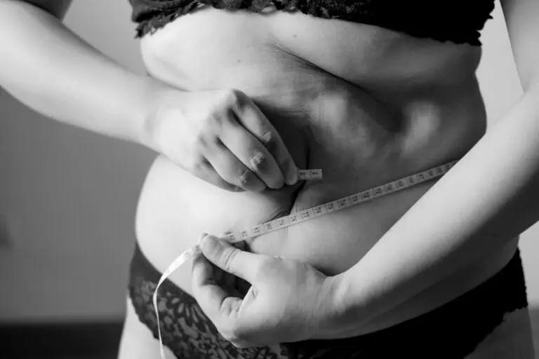 Overweight woman with a measuring tape around her waist.