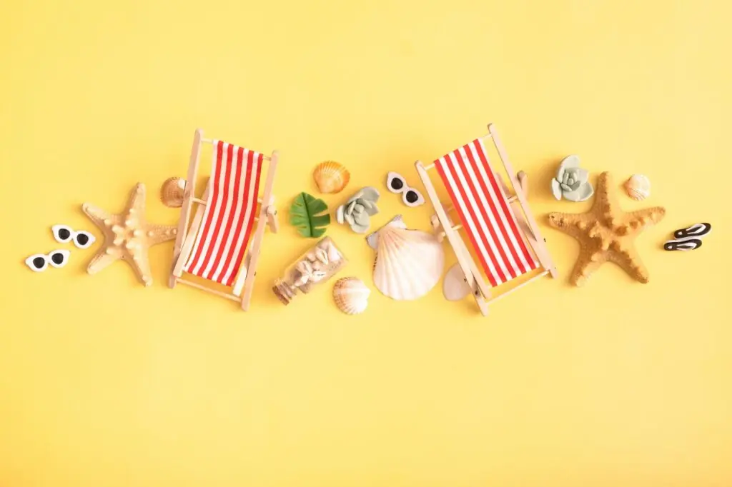 Seashells, folding beach chairs and starfish, on a yellow background. Still life of summer vacation