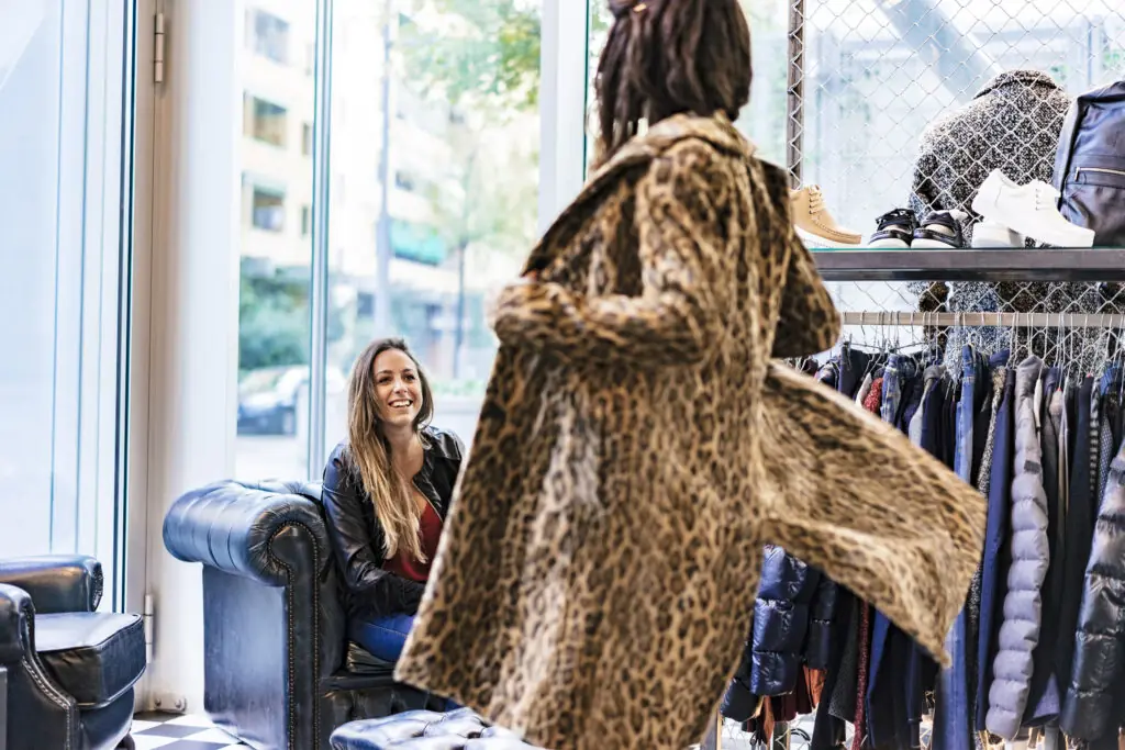 Animal print long coat- two ladies trying on clothes.