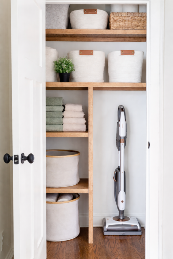 hall closet with towels and vacum cleaner and baskets